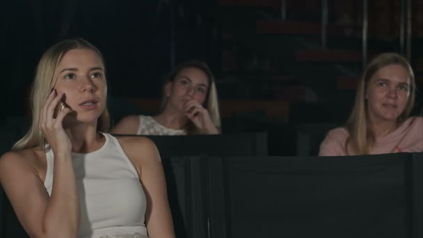 Mujer joven al teléfono durante la película en el cine — Vídeos de Stock