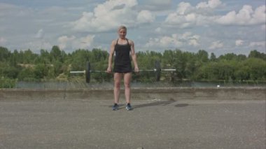 Sportif kadın Barbell ile şehir su kenarındaki arka plan üzerinde egzersiz