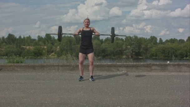 Молодая фитнес-женщина работает с штангой на открытом воздухе — стоковое видео