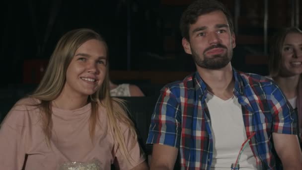 Belo casal rindo e sussurrando para seu homem durante um filme no cinema — Vídeo de Stock