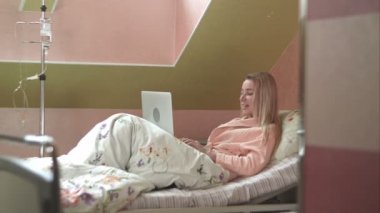 Hastane yatağında görüntülü sohbet sahip dizüstü bilgisayar kullanan genç kadın