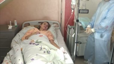 Usta pratisyen damlalık hastanede koyuyor. Genç kadın doktor anestezi damlalık hastane odasında koyar, hemşire hasta tıbbi damla bir damar içine koyar.