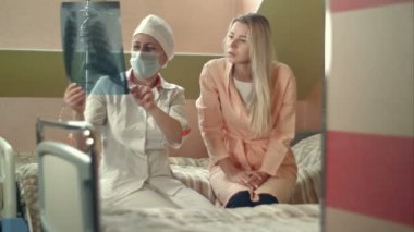 X-ışını tutarak ve genç kadın hasta yatağında oturup konuşmak profesyonel doktor