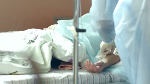 Verpleegkundige voorleggen een druppelaar met een patiënt arm in ziekenhuis kamer — Stockvideo