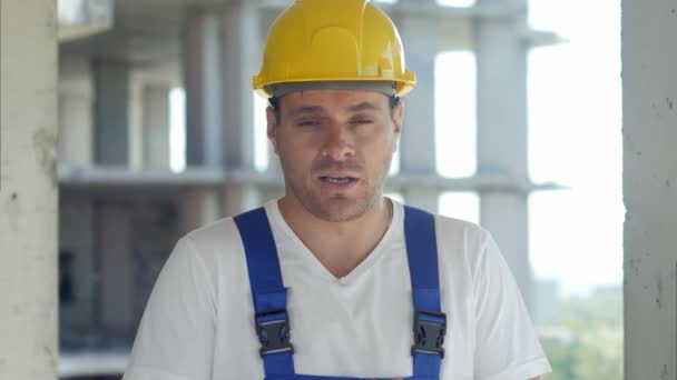 Trabalhador da construção fala com câmera na frente do canteiro de obras — Vídeo de Stock