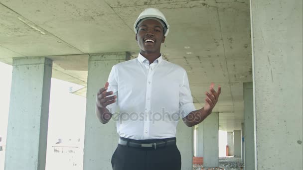 Homme d'affaires africain riant à la zone de construction présentant quelque chose regardant la caméra — Video