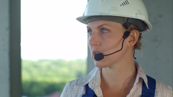 Ingénieur constructeur femelle envisage un plan pour la nouvelle construction et parler via microphone — Video