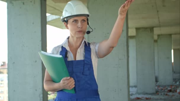 Supervisor constructor supervisa el sitio de construcción y da instrucciones a los trabajadores sobre el intercomunicador — Vídeo de stock