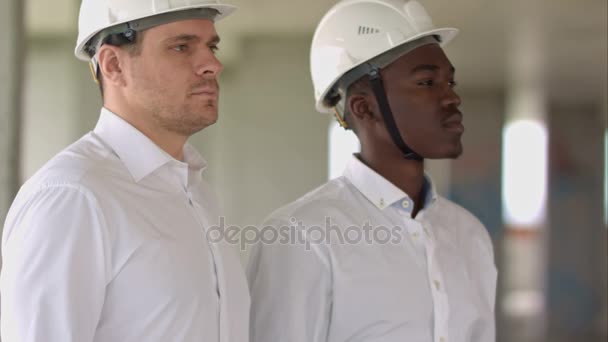 Twee zakenman kijken camera binnen bouwplaats — Stockvideo