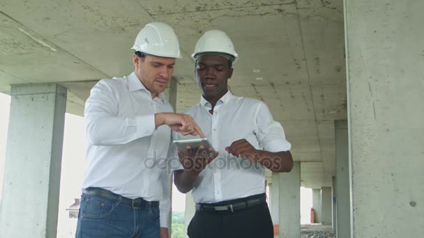 Εκτελεστική ομάδα σε εργοτάξιο επανεξέταση με tablet επίσημα ντυμένοι άνθρωποι ανάγνωση δισκίο κατασκευή μπροστά από το κτίριο — Αρχείο Βίντεο
