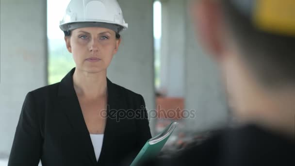 Будівництво жінки, що слухає колегу в офісній будівлі — стокове відео