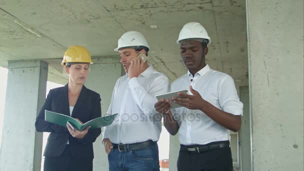 Grupo de engenheiros e especialistas discutem sobre canteiro de obras — Vídeo de Stock