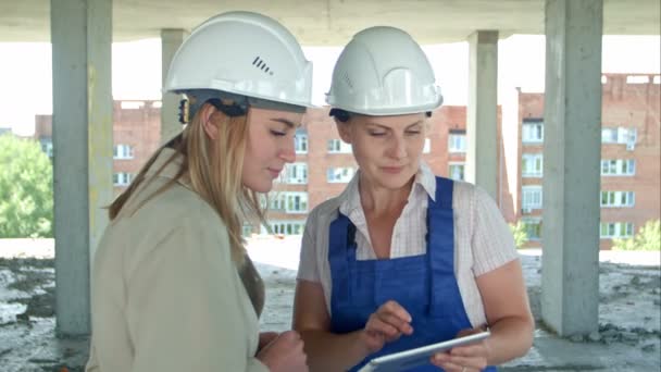 Kvinnlig ingenjör och arbetstagare på byggarbetsplatsen med plan på digitala tablett — Stockvideo