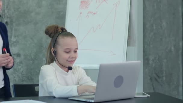 忙しい女の子は、ノート パソコンとヘッドフォンを使用してのオフィスで作業 — ストック動画