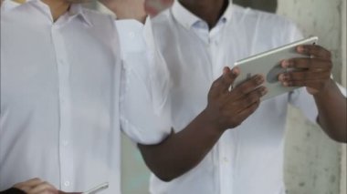 İnşaat alanında tablet bilgisayarı ve akıllı telefonları olan bir grup gülümseyen inşaatçı.