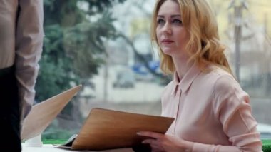 Menü kartı veren holding kafede oturan neşeli genç kadın garsona sipariş