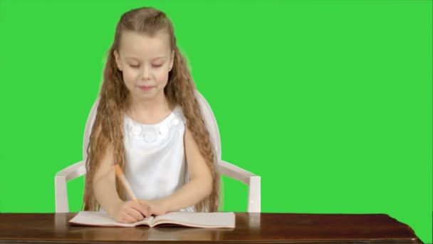 Маленькая девочка пишет для написания книги на зеленом экране, Chroma Key — стоковое видео