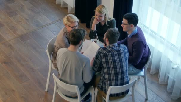 Komunikaci v týmu, skupině pěti lidí diskutovat o něco s úsměvem zatímco sedí u stolu office — Stock video