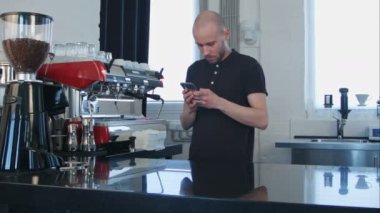 Erkek barista iş yerinde Smartphone kullanarak