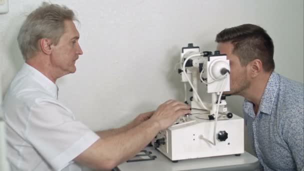 Óptico masculino examinando la presión ocular de los pacientes — Vídeo de stock