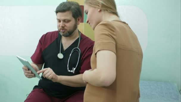 Médico e mulher grávida olham para tablet digital juntos — Vídeo de Stock