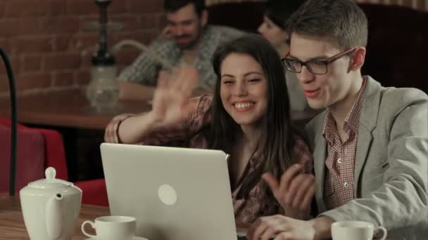 Par skrattar och ha en videokonferens på en laptop, medan röka vattenpipa — Stockvideo