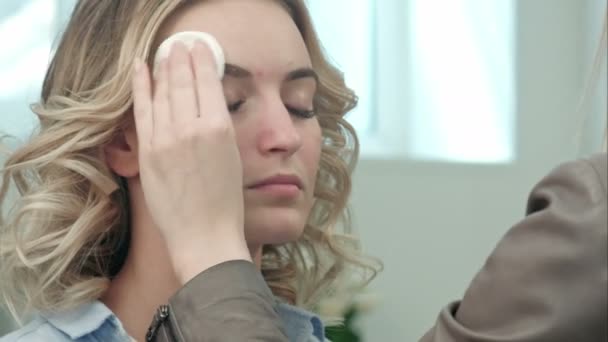 Визажист чистит кожу на модельном лице — стоковое видео