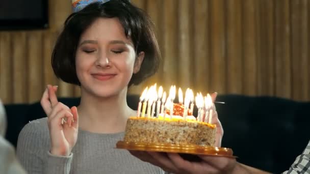 Молодая девушка задувает свечи на торте — стоковое видео