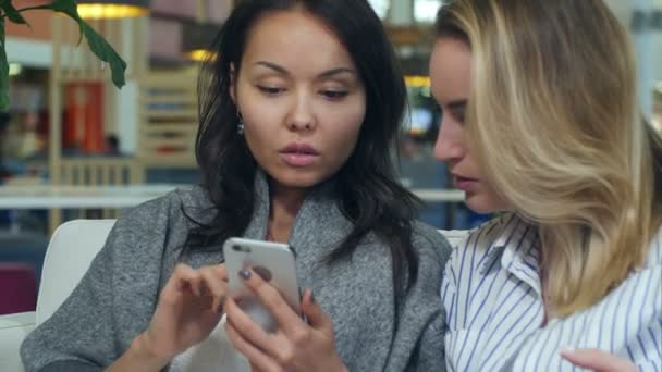 Mutlu alışveriş Asya kadın sarışın arkadaşı bir alışveriş merkezi ile smartphone kullanın — Stok video