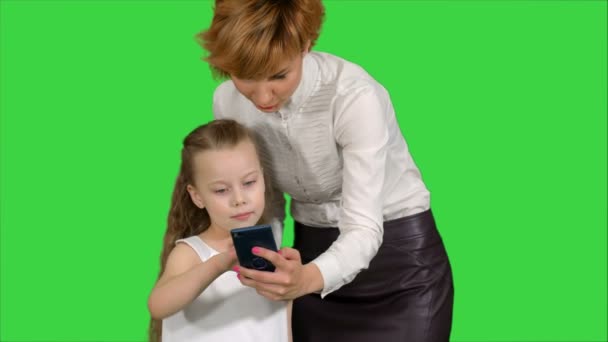 Jovem mãe ensinando sua filha como usar o smartphone em uma tela verde, Chroma Key — Vídeo de Stock