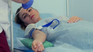 Becerikli hemşire damlayan ilaç için kadın hasta koluna damar içi enjeksiyon yapıyor.