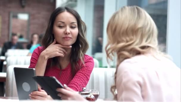 Two beautiful females in cafe using digital tablet — Stock Video