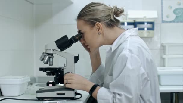Mujer sorprendida trabajando con un microscopio en laboratorio — Vídeos de Stock