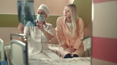 X-ışını tutarak ve genç kadın hasta yatağında oturup konuşmak profesyonel doktor