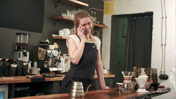 У молодої власниці кав'ярні є телефонний дзвінок за допомогою смартфона в кафетерії — стокове відео