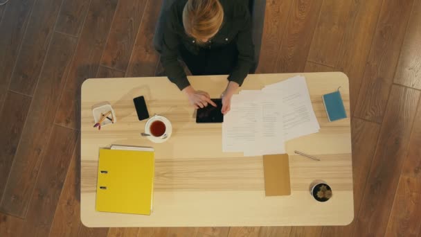 Attraktive Geschäftsfrau, die ein digitales Tablet benutzt, während sie am Schreibtisch vor dem Fenster in einem Büro sitzt — Stockvideo