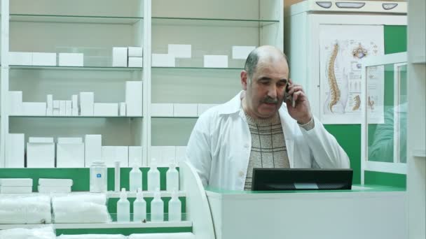 Conversación farmacéutica con el cliente mediante teléfono móvil en farmacia — Vídeo de stock