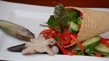 Bir tabakta sebze salatası için deniz ürünleri koyarak