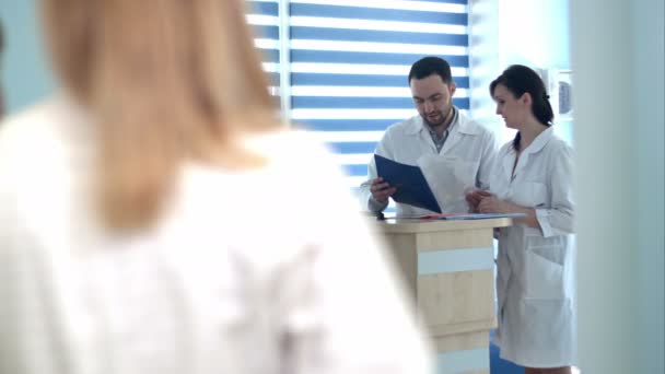 Врачи просматривают папки пациентов на стойке регистрации в больнице — стоковое видео