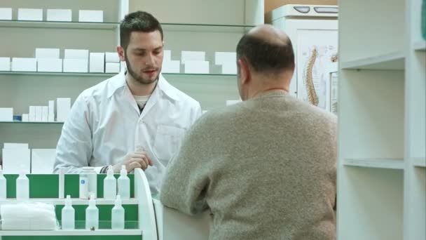 Старший чоловік приходить в аптеку, щоб купити таблетки або таблетки — стокове відео