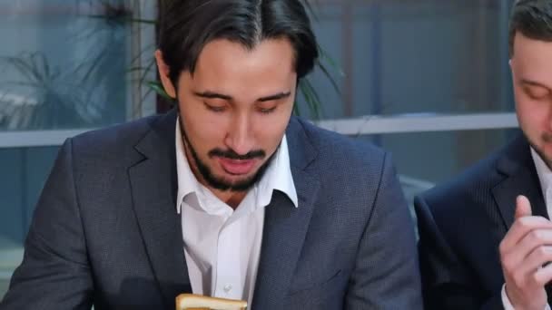 Dos hombres de negocios comiendo sándwich en el almuerzo en la oficina — Vídeo de stock