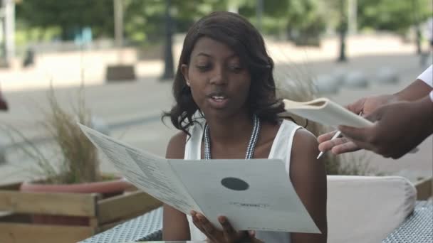 Atractivo impresionante joven afro-americana dama sentada sola en la mesa de la cafetería, listo para hacer orden — Vídeos de Stock