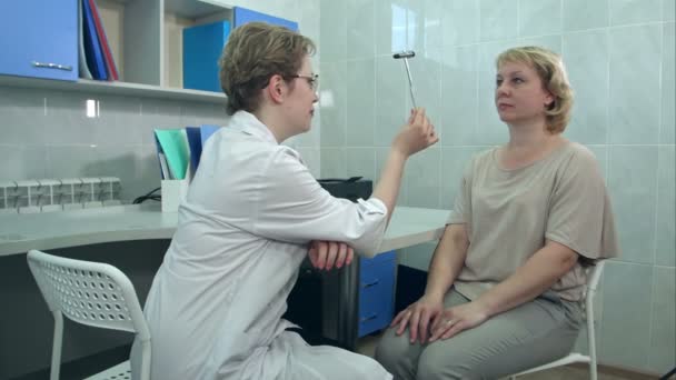 Жіночий невролог, який проводить неврологічні тести на пацієнта в офісі — стокове відео