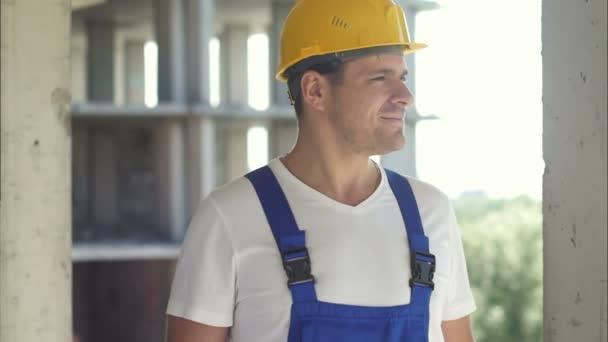 Trabajador de la construcción sonriendo y mirando hacia otro lado sobre un fondo del cielo — Vídeos de Stock