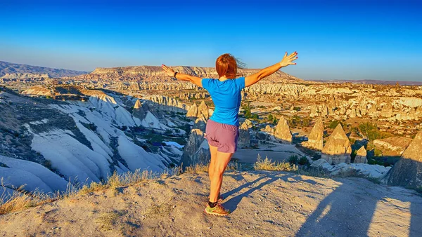 Vista desde la parte posterior de una niña se para en una colina y mira synset en Capadocia, Turquía . —  Fotos de Stock