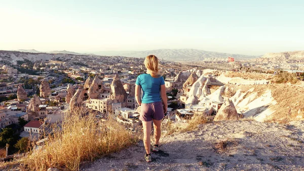 Vista desde la parte posterior de una niña se para en una colina y mira synset en Capadocia, Turquía . —  Fotos de Stock