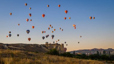 Kapadokya Türkiye 'de kayaların üzerinde uçan sıcak hava balonu