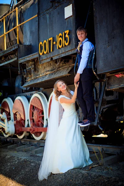 Portret van verheugd huwelijksfeest paar in de buurt van de oude stoomlocomotief — Stockfoto