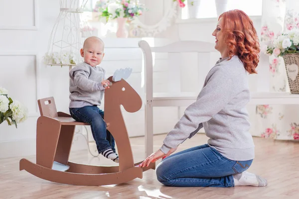 Feliz lindo niño pequeño montar madera mecedora caballo mamá —  Fotos de Stock