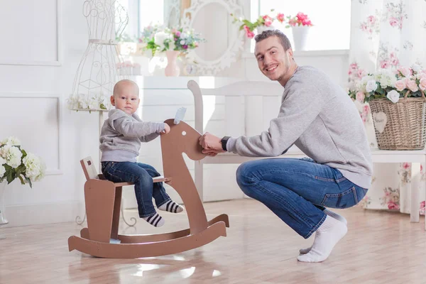 Feliz niño montando madera mecedora caballo papá —  Fotos de Stock